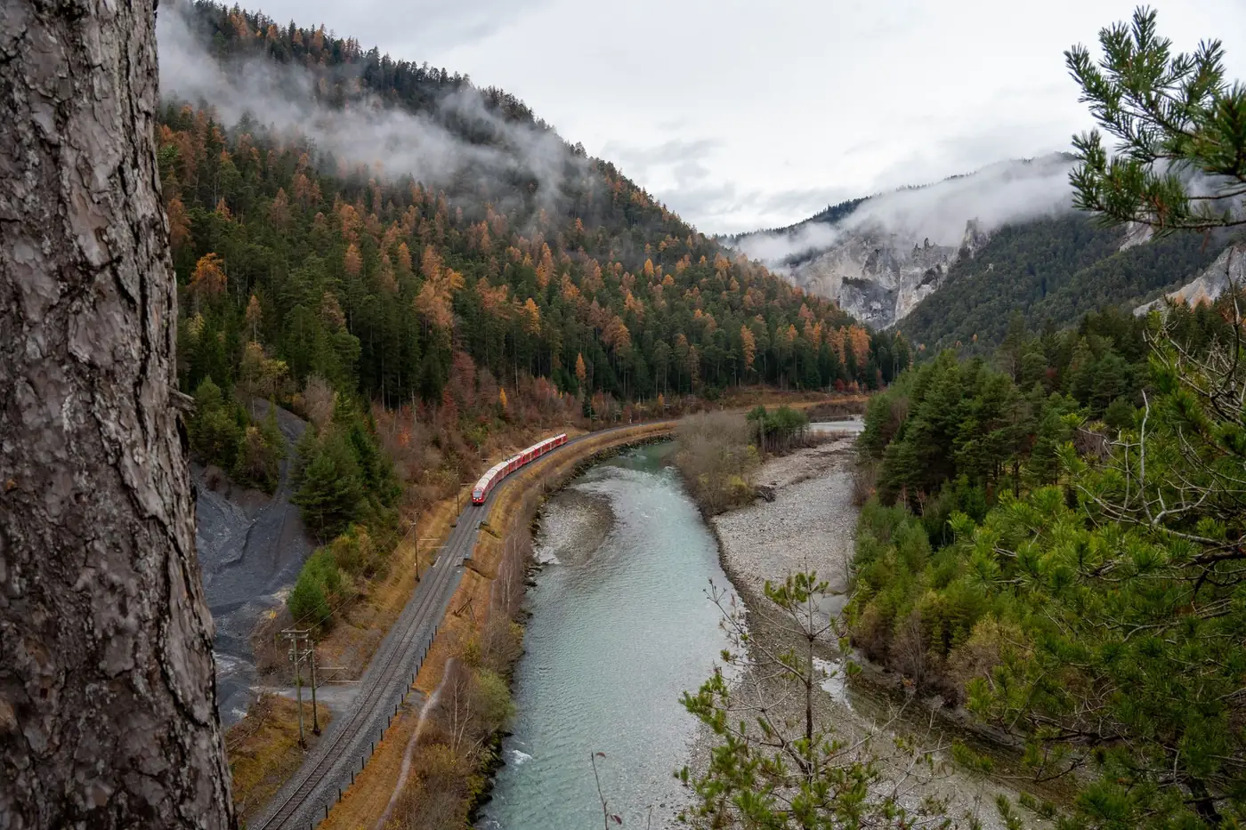 Rode trein die door een Zwitsers alpendal met herfstkleuren rijdt