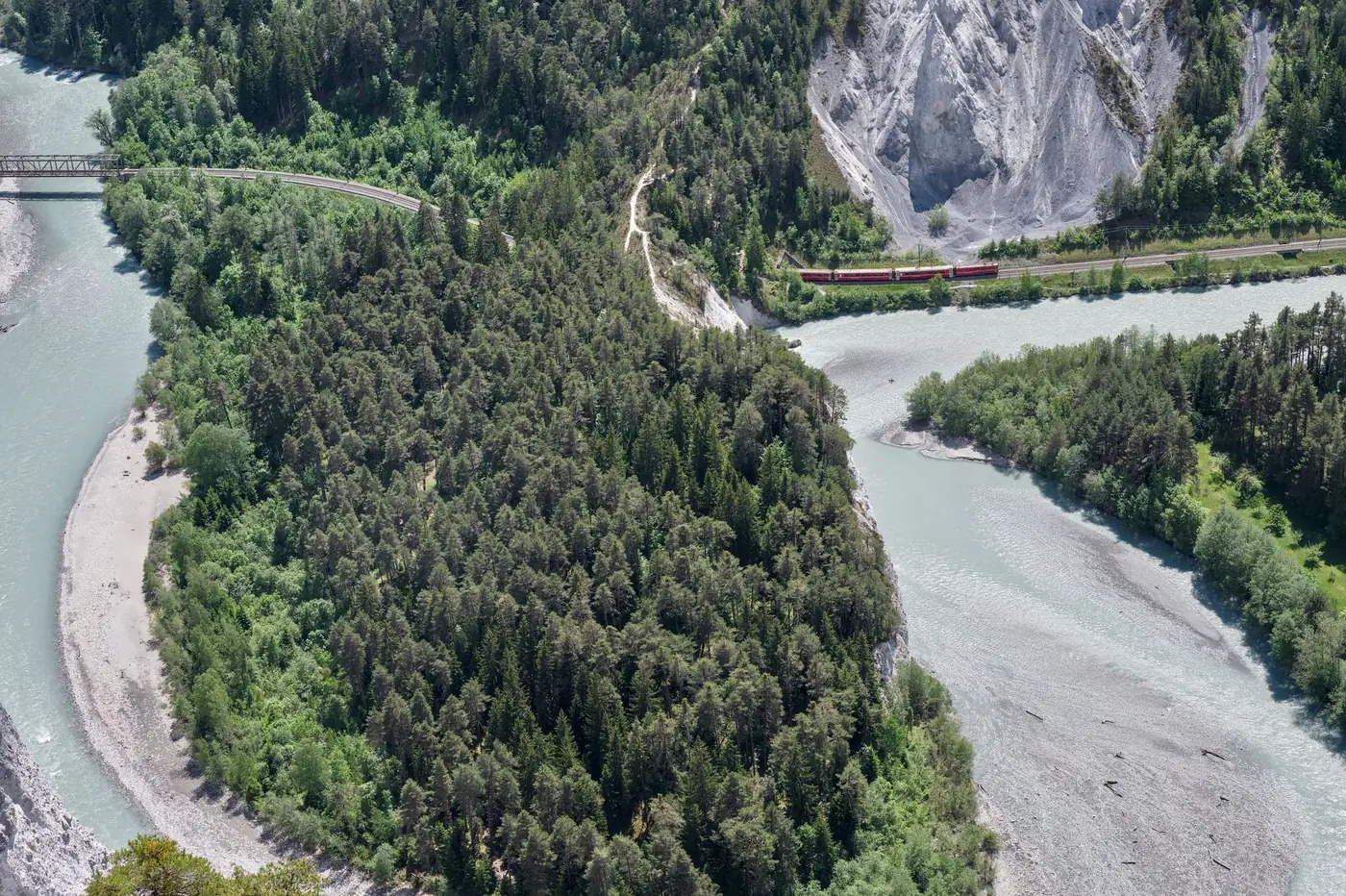 Rode panoramatrein die door een Zwitserse bergkloof met bos rijdt