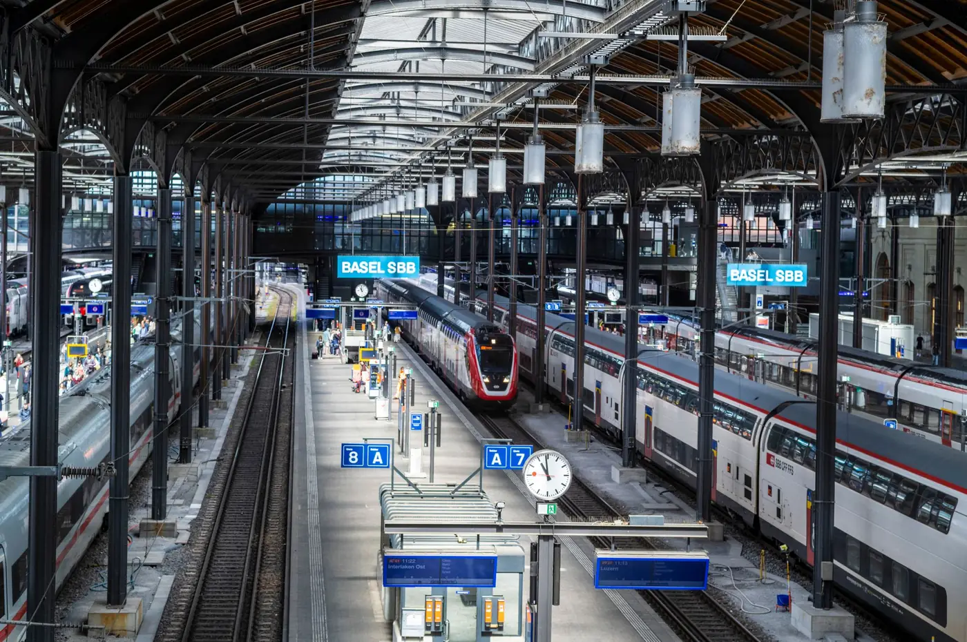 Treinstation in Zwitserland met meerdere sporen en reizigers op het perron