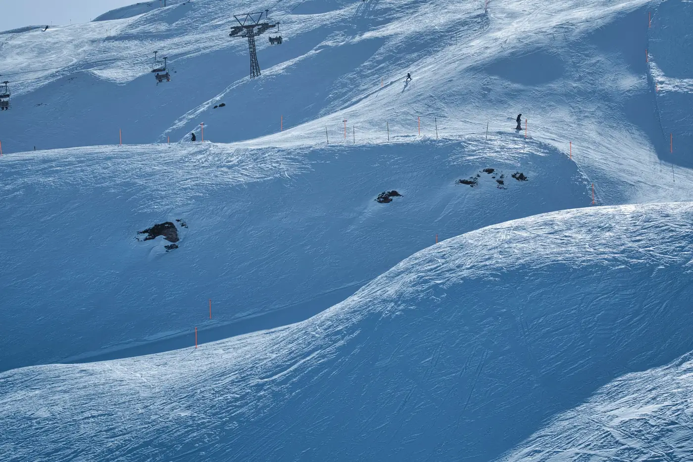 Skiër op een besneeuwde piste met een stoeltjeslift op de achtergrond