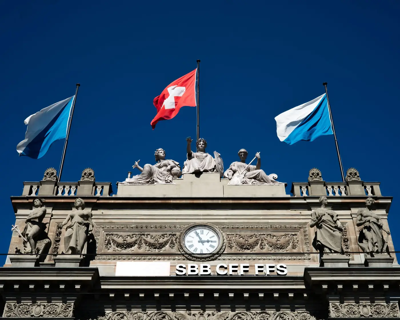 Historisch gebouw met Zwitserse vlaggen en beeldhouwwerk in Zürich