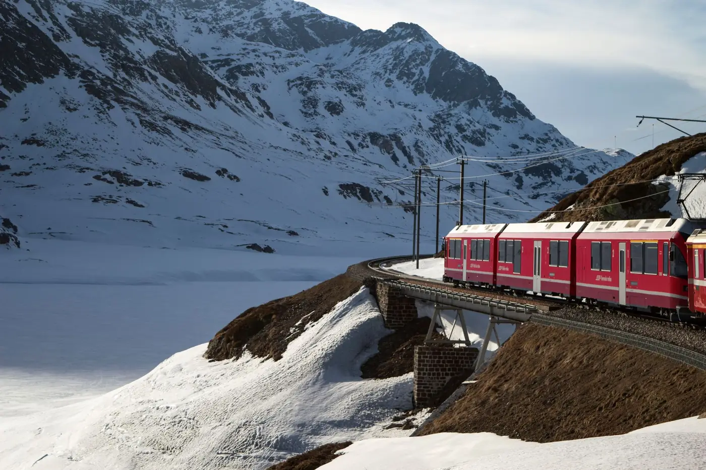 Rode Bernina Express trein die in de winter door besneeuwde Zwitserse Alpen rijdt