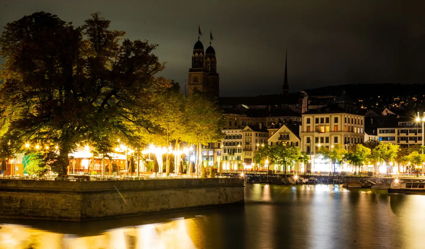 Verlichte straten van Zürich in de avond met de Grossmünster op de achtergrond