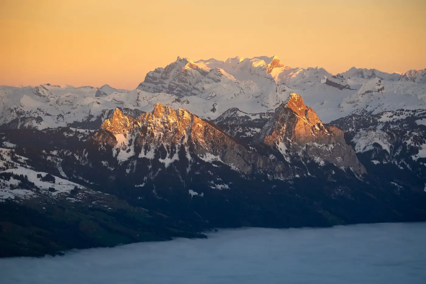 Breathtaking view of snow-capped mountains illuminated by sunset glow, capturing winter's majestic beauty.