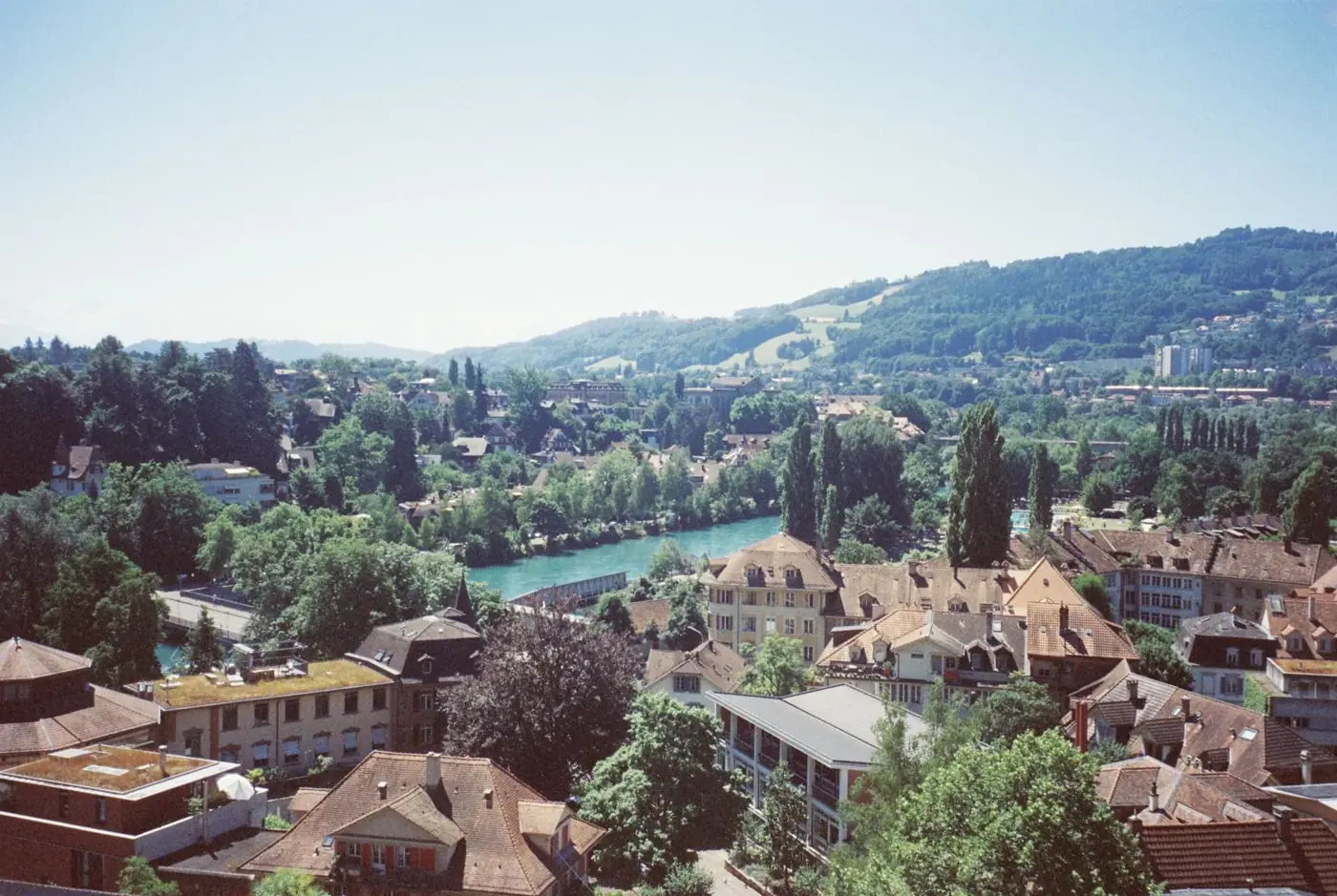 A scenic aerial view of a quaint Swiss town with lush greenery and a winding river.