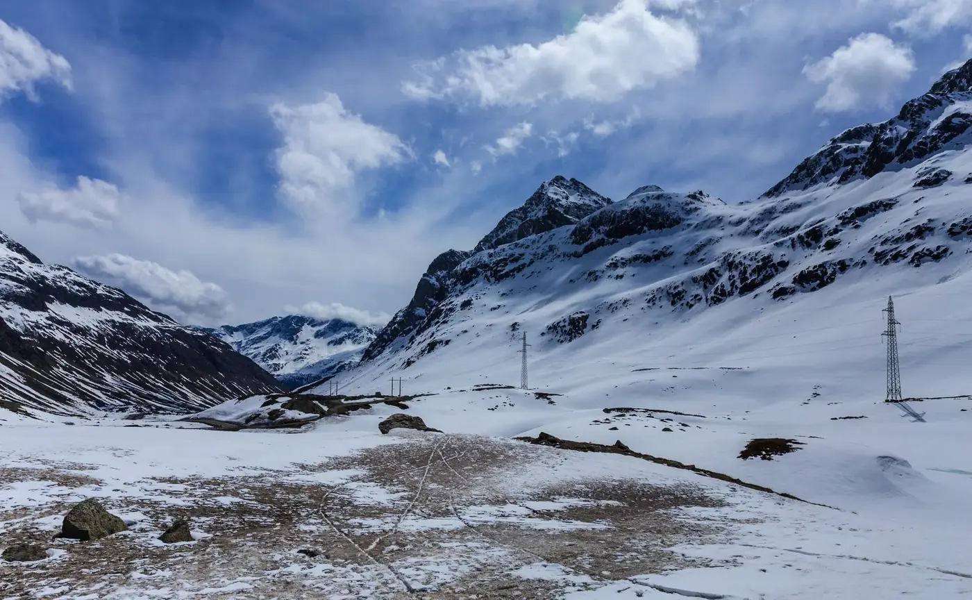 Scenic winter landscape of snow-covered mountains in Bivio, Switzerland with blue skies.