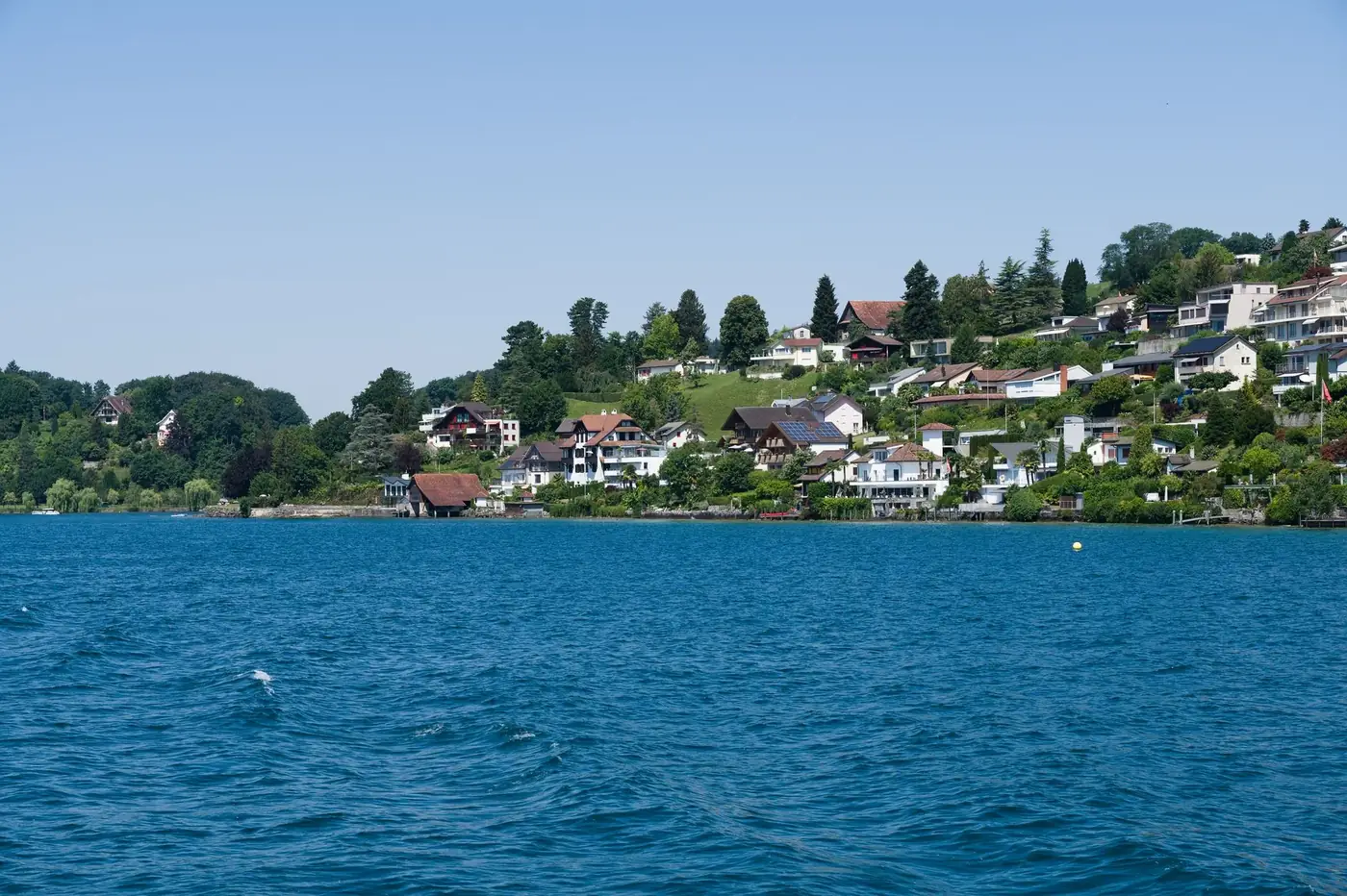 Picturesque landscape of lakefront homes in the Swiss countryside, capturing serene beauty and lush greenery.