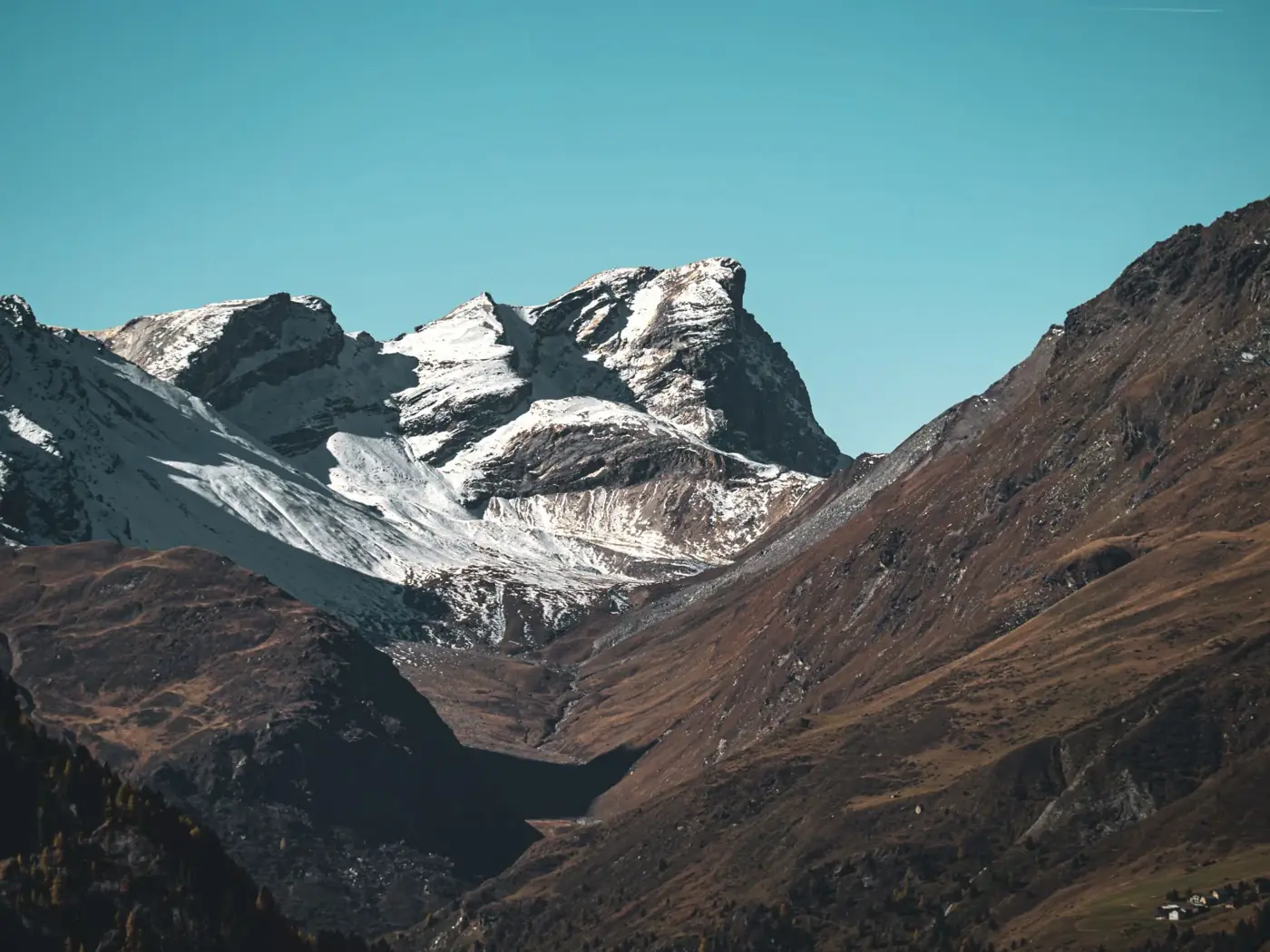 Breathtaking view of snow-capped mountains in Surses, Graubünden, Switzerland, showcasing winter's rustic charm.