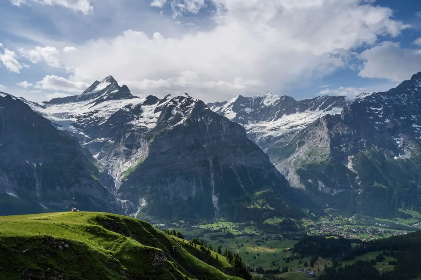 Panoramic view of the Swiss Alps in the Jungfrau region with lush green valleys and snow-capped peaks.
